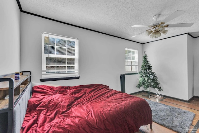 bedroom with ceiling fan, crown molding, baseboards, and a textured ceiling