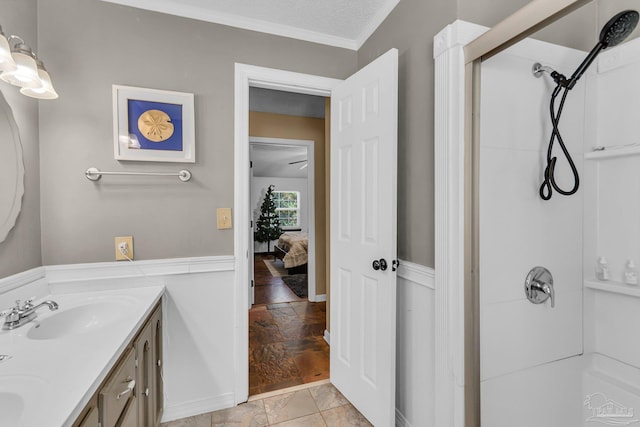 full bathroom with double vanity, a sink, a textured ceiling, crown molding, and a shower