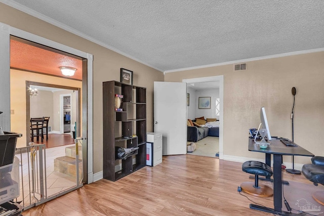 office area featuring visible vents, ornamental molding, a textured ceiling, light wood-style floors, and baseboards