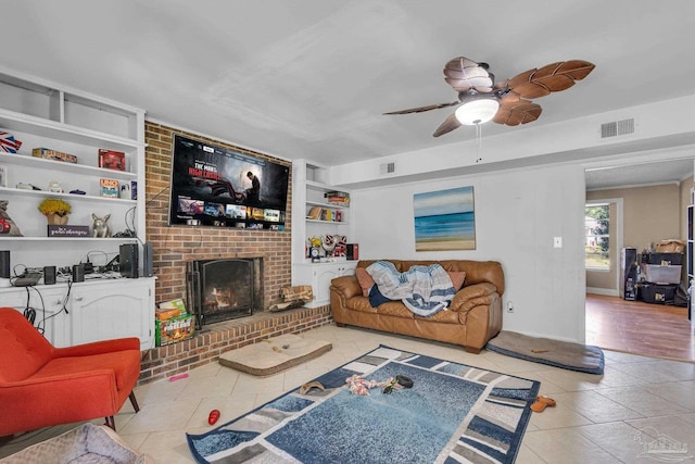 tiled living room featuring visible vents, built in shelves, a fireplace, and a ceiling fan