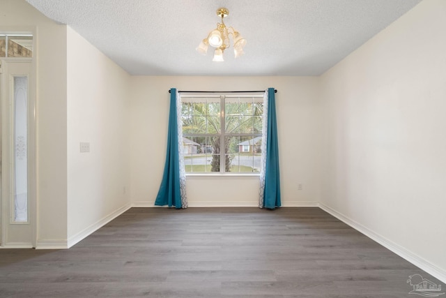 unfurnished dining area with dark wood-type flooring, a textured ceiling, and a notable chandelier