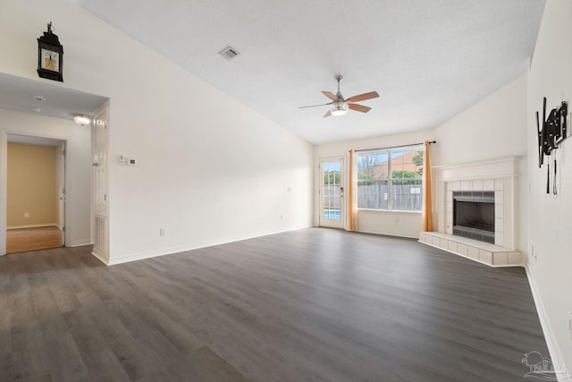 unfurnished living room with dark wood-type flooring, vaulted ceiling, a tile fireplace, and ceiling fan