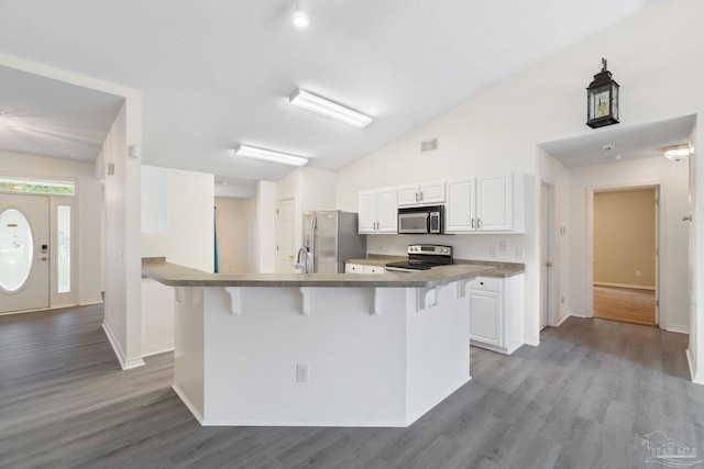 kitchen featuring lofted ceiling, a breakfast bar area, appliances with stainless steel finishes, white cabinetry, and light wood-type flooring