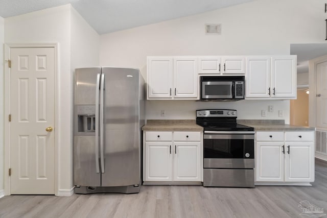 kitchen featuring lofted ceiling, appliances with stainless steel finishes, and white cabinets