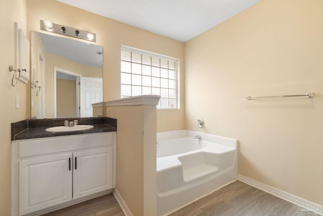 bathroom with hardwood / wood-style floors, vanity, a washtub, and a textured ceiling