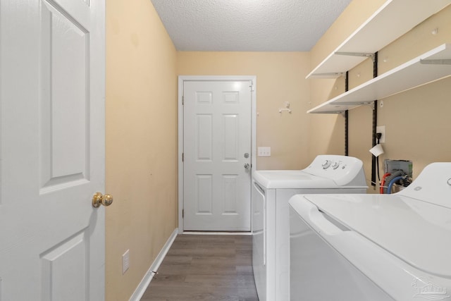 laundry area featuring hardwood / wood-style flooring, washing machine and dryer, and a textured ceiling