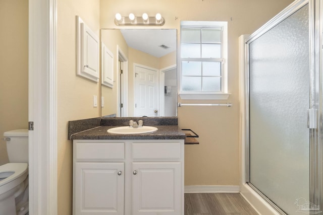 bathroom with wood-type flooring, toilet, vanity, and a shower with shower door