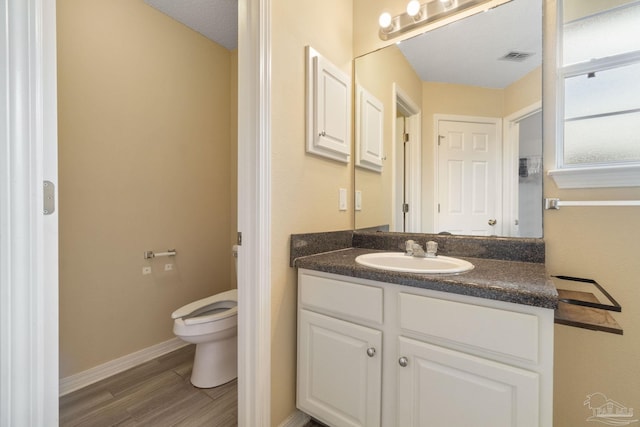 bathroom with wood-type flooring, vanity, a textured ceiling, and toilet