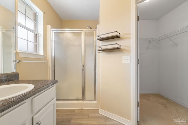 bathroom featuring an enclosed shower, vanity, wood-type flooring, and a textured ceiling