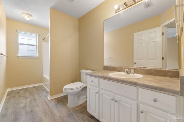 full bathroom featuring hardwood / wood-style flooring, vanity, toilet, a textured ceiling, and washtub / shower combination