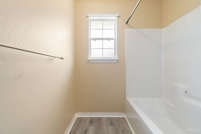 bathroom with wood-type flooring and  shower combination