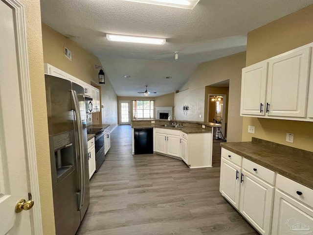 kitchen with lofted ceiling, sink, appliances with stainless steel finishes, kitchen peninsula, and white cabinets