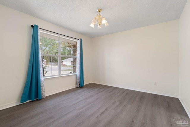 spare room with hardwood / wood-style flooring, a textured ceiling, and an inviting chandelier