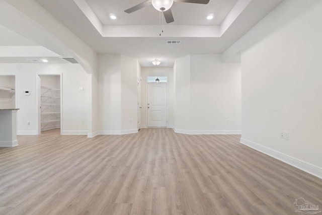 unfurnished room with a raised ceiling, ceiling fan, and light hardwood / wood-style floors