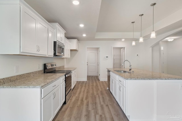 kitchen featuring light stone countertops, a center island with sink, appliances with stainless steel finishes, sink, and white cabinets