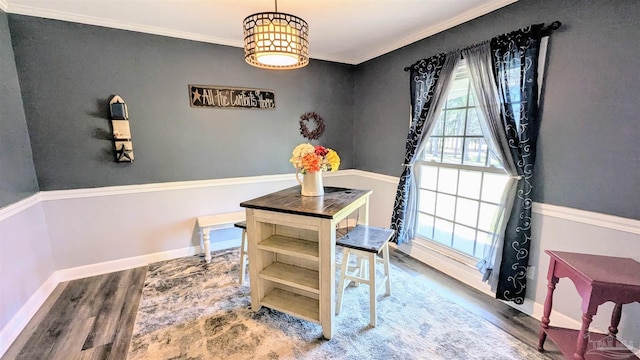 dining space featuring baseboards, wood finished floors, and ornamental molding