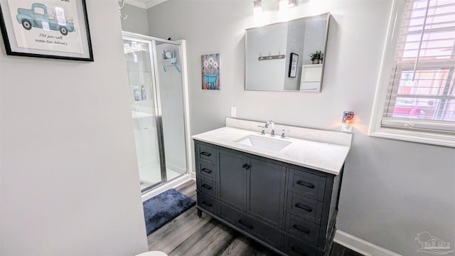 full bath with vanity, wood finished floors, a stall shower, and baseboards