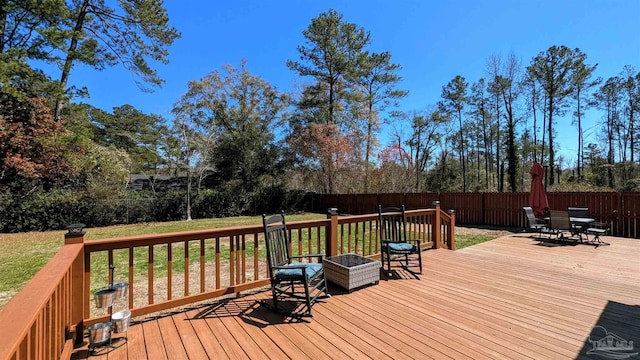 deck with outdoor dining area, a yard, and a fenced backyard