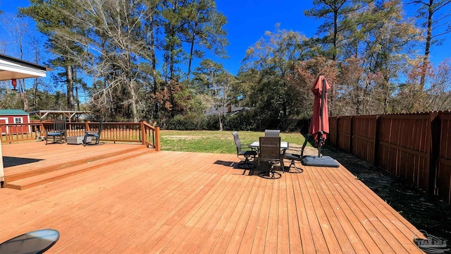 wooden deck with outdoor dining space, a lawn, and a fenced backyard