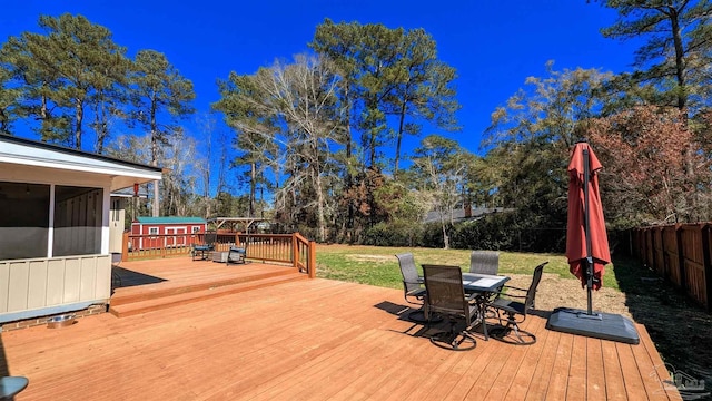 wooden deck with outdoor dining space, a yard, a fenced backyard, and a sunroom