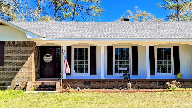 entrance to property with crawl space, brick siding, and a shingled roof