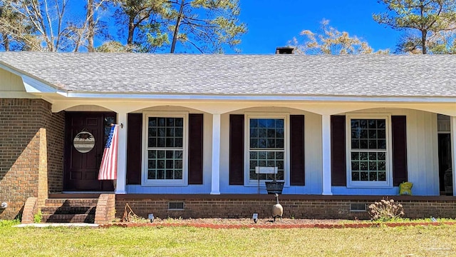 doorway to property featuring crawl space, brick siding, roof with shingles, and covered porch