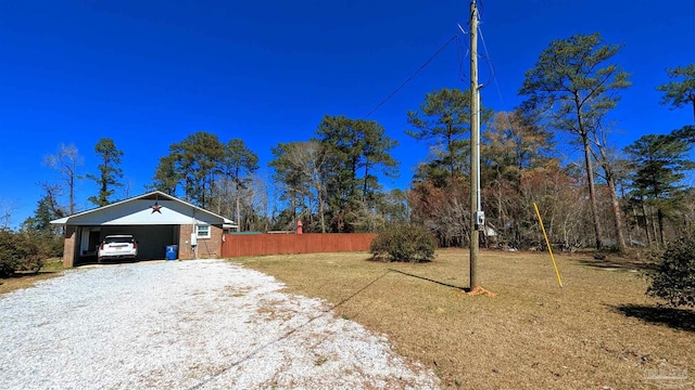 view of yard with a carport, driveway, and fence