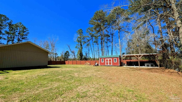 view of yard featuring a carport, a storage shed, an outdoor structure, and fence