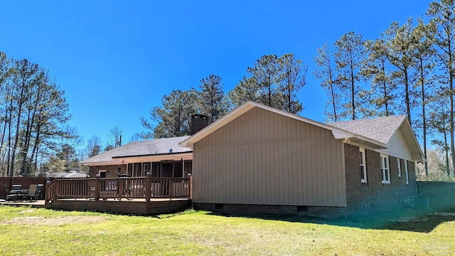 back of property featuring brick siding, a wooden deck, a lawn, a chimney, and crawl space