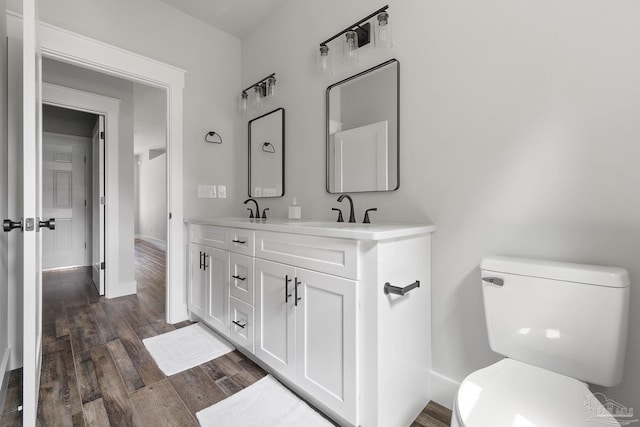 bathroom featuring toilet, vanity, and wood-type flooring