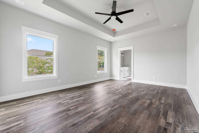 empty room featuring ceiling fan, dark hardwood / wood-style flooring, and a tray ceiling