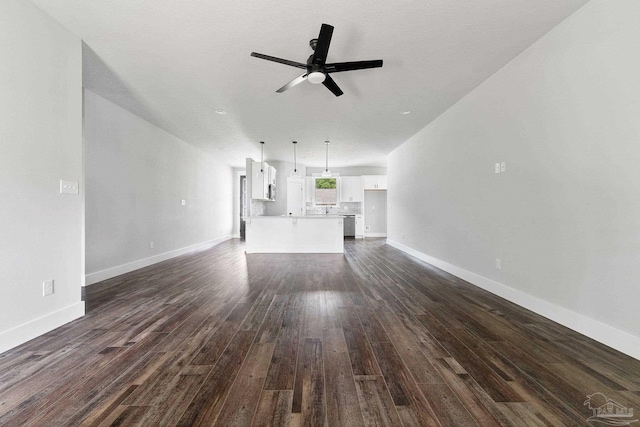 unfurnished living room featuring ceiling fan and dark wood-type flooring