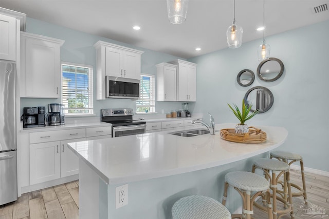 kitchen with a breakfast bar, stainless steel appliances, light countertops, visible vents, and a sink