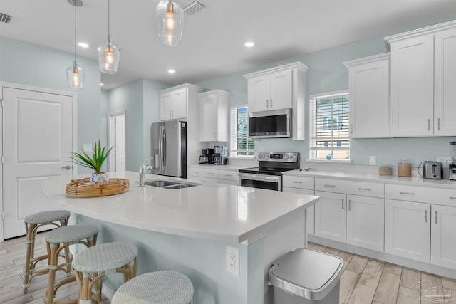 kitchen featuring stainless steel appliances, a breakfast bar, visible vents, white cabinets, and an island with sink