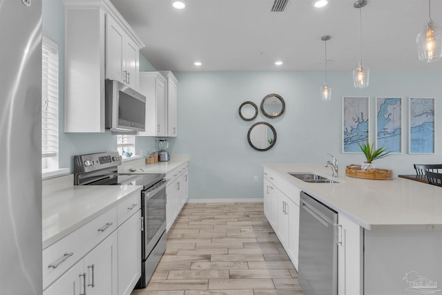 kitchen with appliances with stainless steel finishes, a kitchen island with sink, light countertops, and a sink