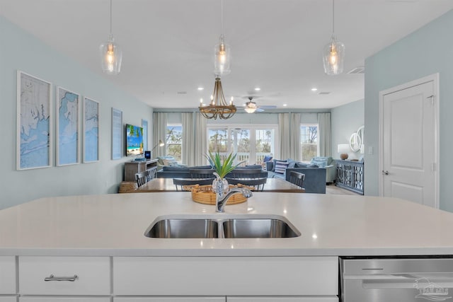 kitchen with stainless steel dishwasher, open floor plan, a sink, and light countertops