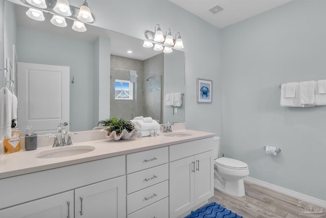 bathroom with visible vents, a sink, a tile shower, and toilet