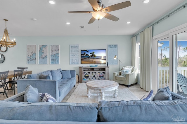 living room featuring ceiling fan with notable chandelier, light wood-type flooring, visible vents, and recessed lighting