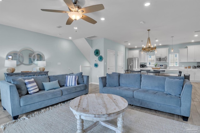 living room with ceiling fan with notable chandelier, visible vents, and recessed lighting