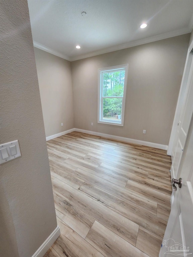 empty room with light wood-type flooring and crown molding