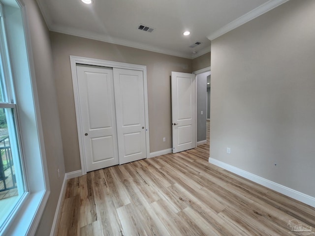 unfurnished bedroom with a closet, light hardwood / wood-style flooring, and crown molding