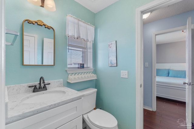 bathroom with vanity, a textured ceiling, hardwood / wood-style floors, and toilet