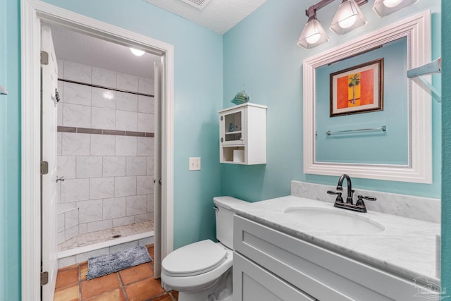 bathroom with vanity, a textured ceiling, a tile shower, tile patterned floors, and toilet