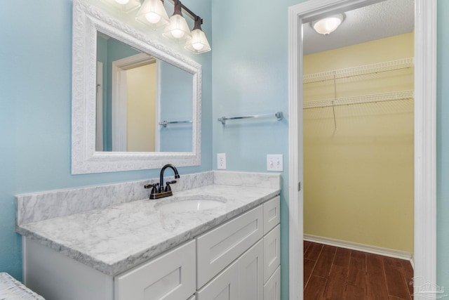 bathroom with hardwood / wood-style floors, vanity, and a textured ceiling