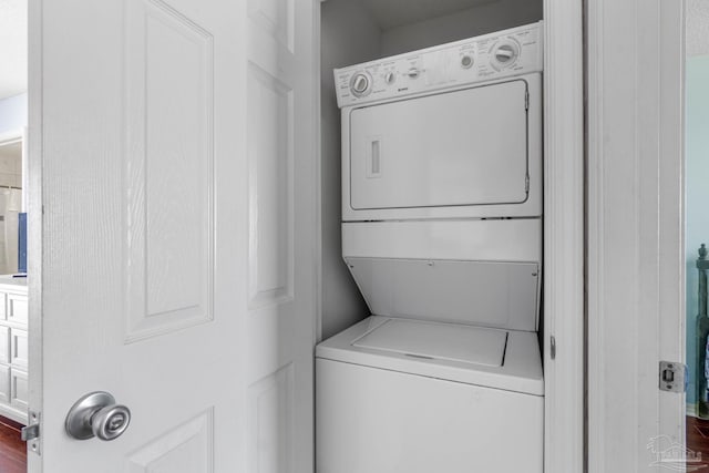 laundry room featuring dark hardwood / wood-style floors and stacked washing maching and dryer