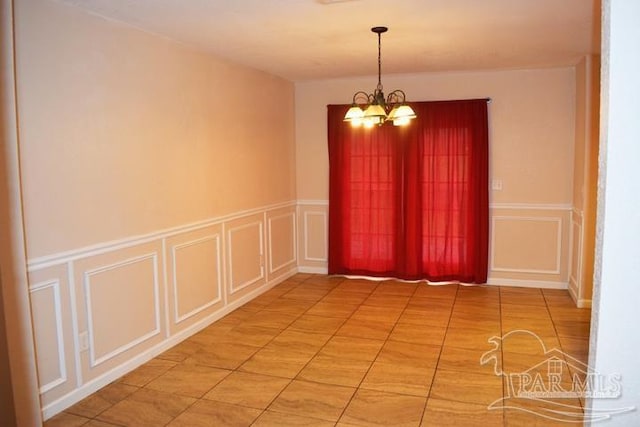 spare room featuring light tile patterned floors and a notable chandelier