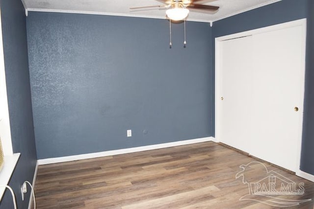 unfurnished bedroom with a closet, ceiling fan, crown molding, and hardwood / wood-style flooring