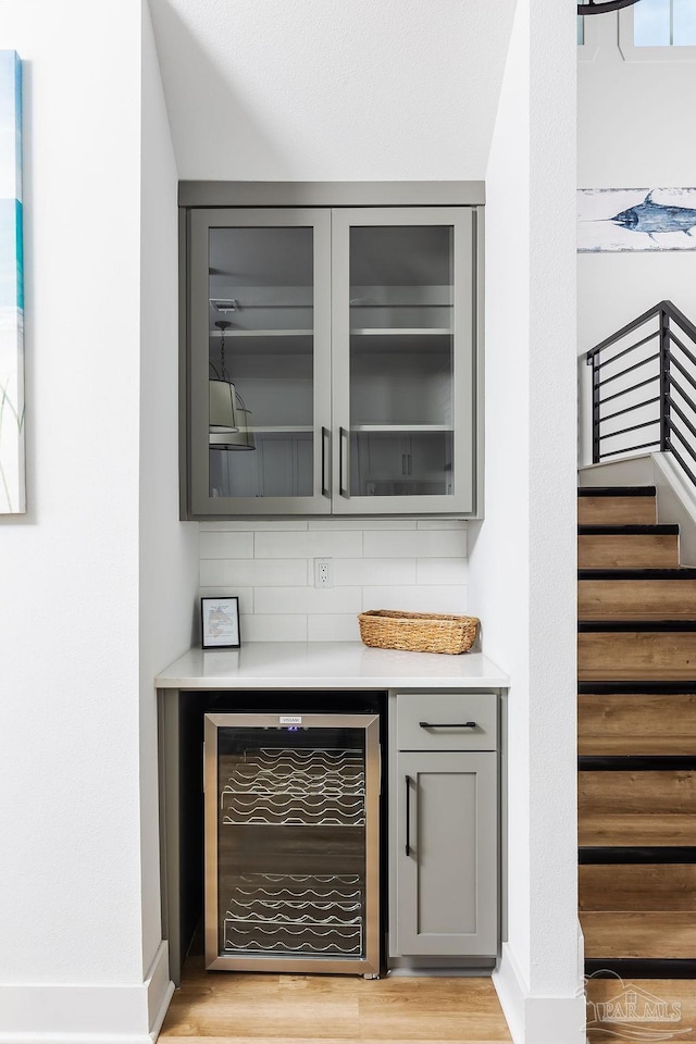 bar featuring tasteful backsplash, beverage cooler, and gray cabinets