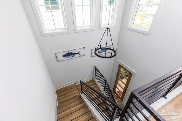 stairs featuring a notable chandelier and wood-type flooring