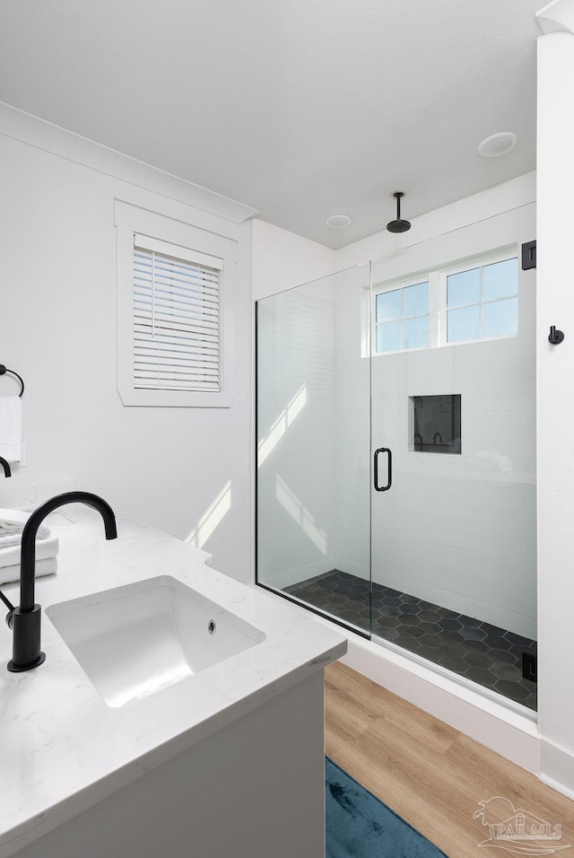 bathroom with wood-type flooring, a shower with shower door, and vanity